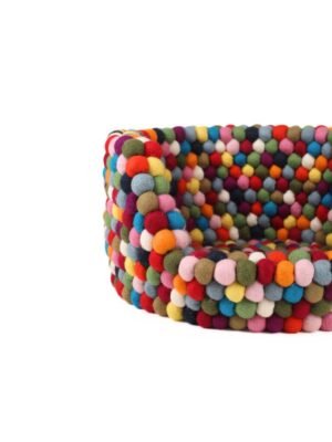 Nestled in a cloud of handmade felt balls, this dog bed promises plush relaxation and playful texture.