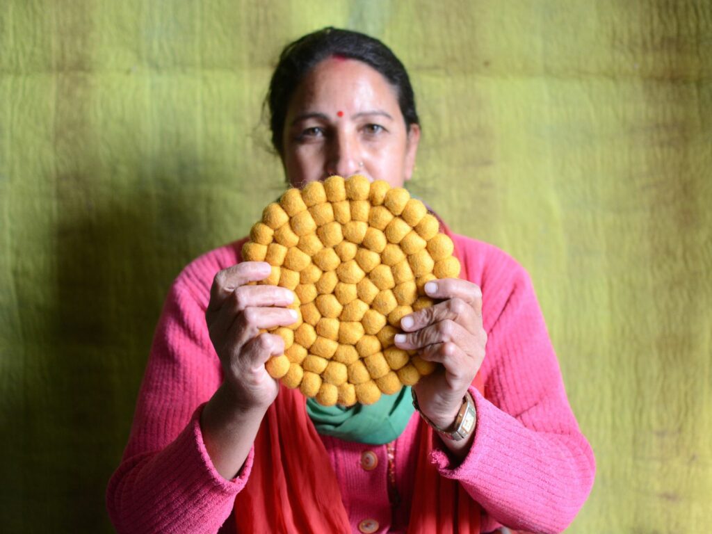 a craftswomen with handmade felt ball trivets 
